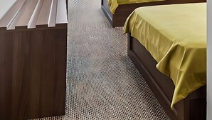 Ein Hotelzimmer mit zwei Betten, einem Schreibtisch, einem Stuhl, einem Fernseher und einem Fenster mit Vorhängen.