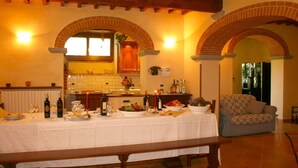 A dining area with a long table set for a meal, a kitchen in the background, and a patterned sofa. - Private Villa with AC, private pool, WIFI, TV, terrace, pets allowed, parking, close to Arezzo (Castiglion Fiorentino)