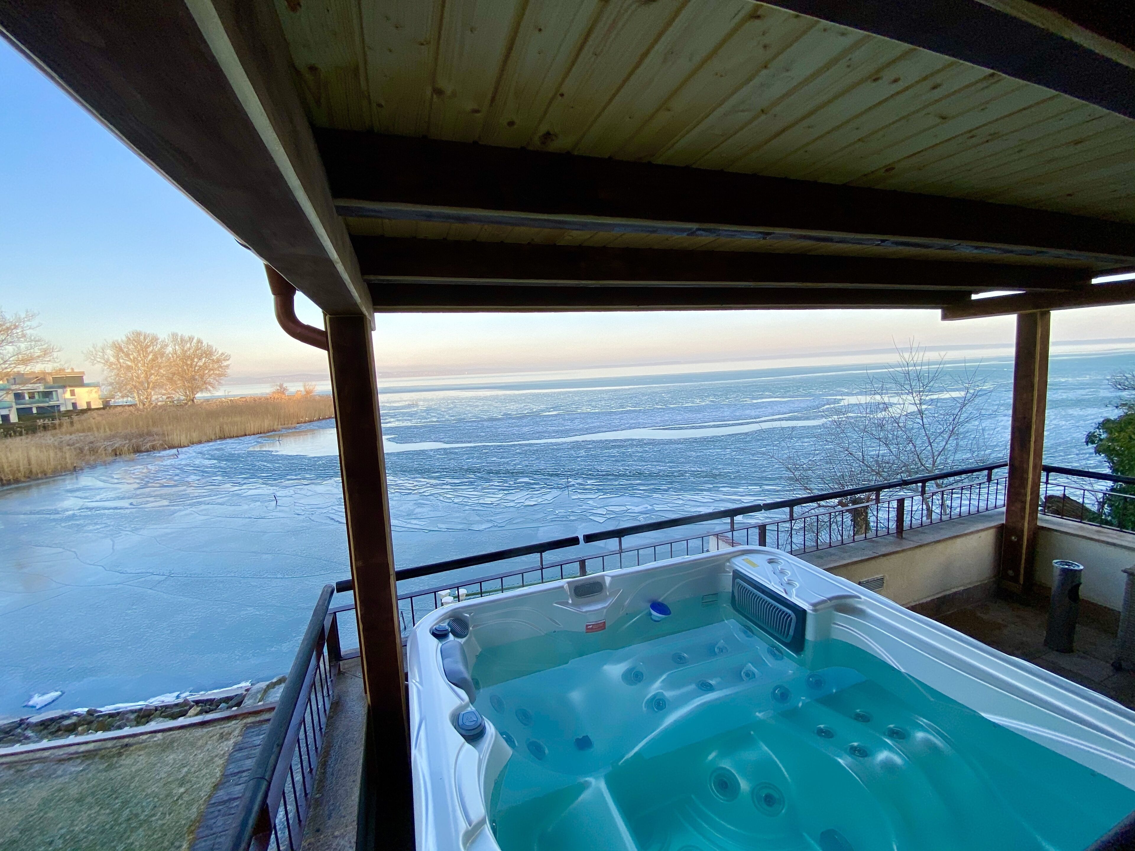 Een hottub met uitzicht op een bevroren meer en een houten terras.