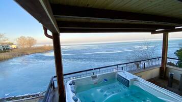 Een hottub met uitzicht op een bevroren meer en een houten terras.