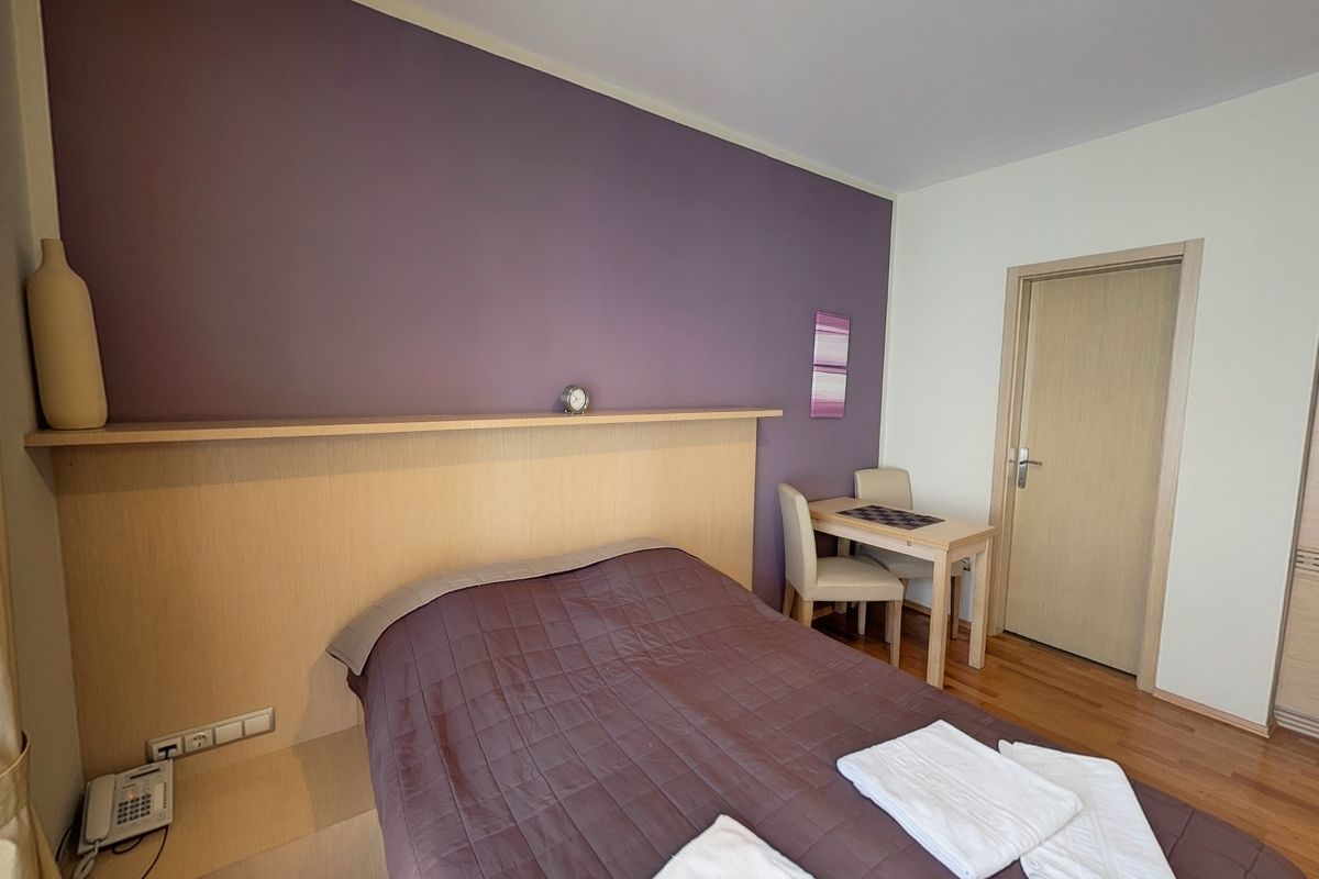 Una habitación de hotel con cama, escritorio, silla, teléfono y puerta.
