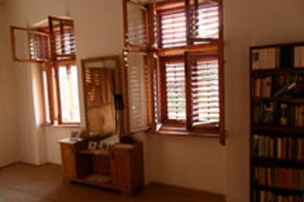 A room with a wooden cabinet, a bookshelf, and a window with blinds.