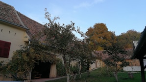 A rustic building with a tiled roof and a small porch. - Casa Arthur (Biertan)
