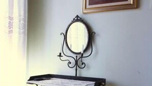 Quarto com um ferro de passar de estilo antigo e um espelho fixado na parede.