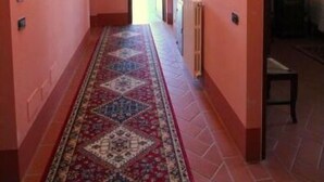 Um corredor com carpete estampado, vigas de madeira no teto e quadros nas paredes.