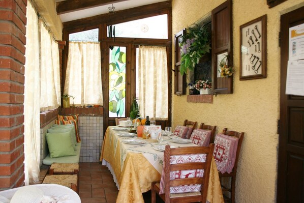 A dining area with a table set for four, a brick wall, and a window with curtains.