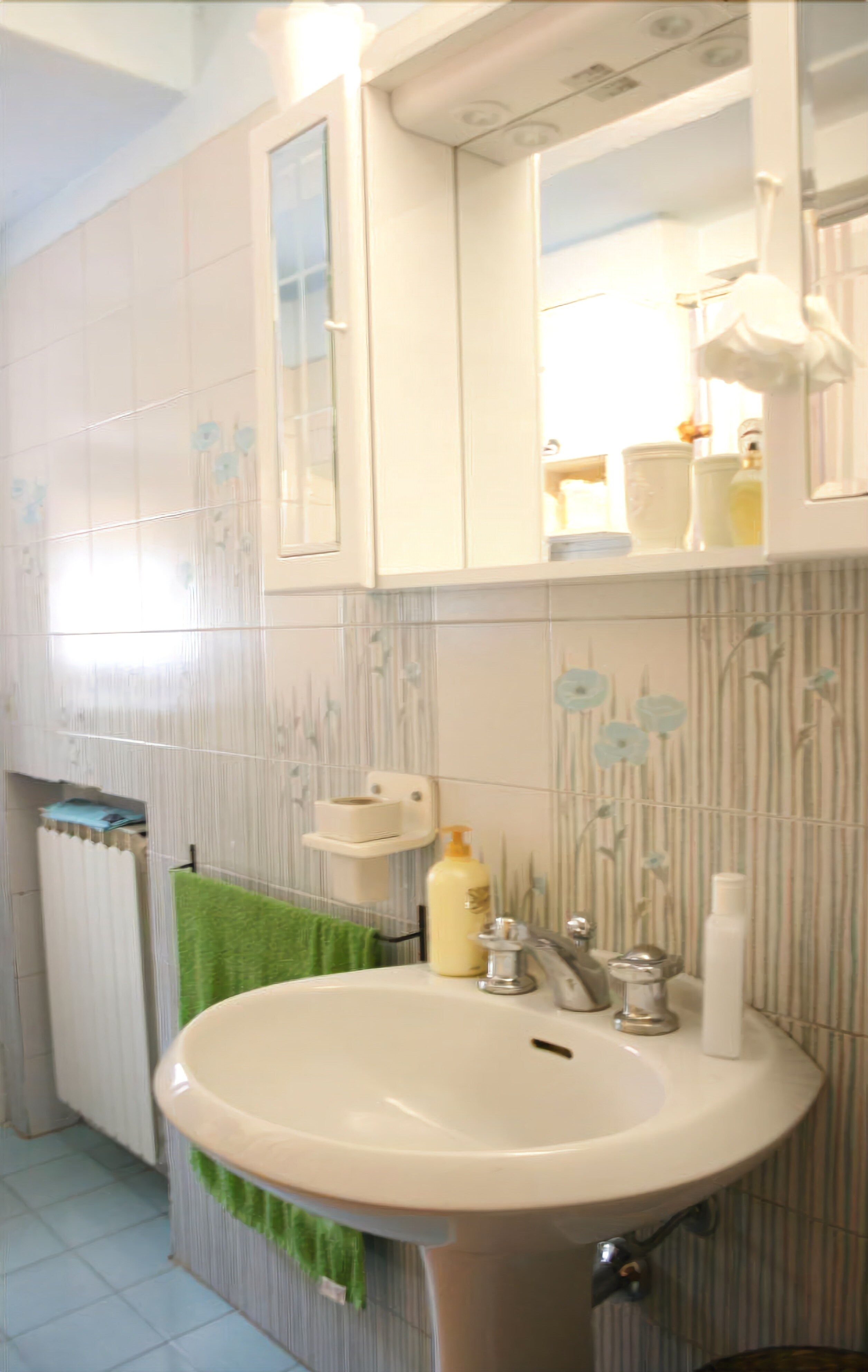 Een badkamer met een wastafel, spiegel en handdoekhouder.