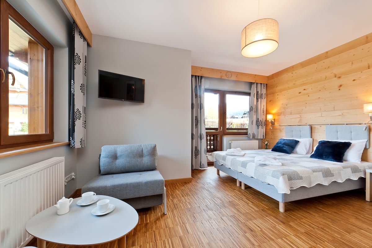 Une chambre d’hôtel confortable, avec un lit, un canapé, une télévision et une fenêtre avec des rideaux.