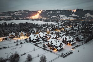 Een besneeuwd dorpje met traditionele houten huizen, een piste en een verafgelegen, verlichte berg.