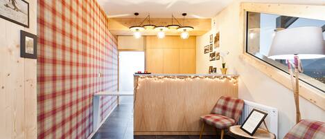 A cozy kitchen with a wooden island, plaid wallpaper, and a window with a lamp.