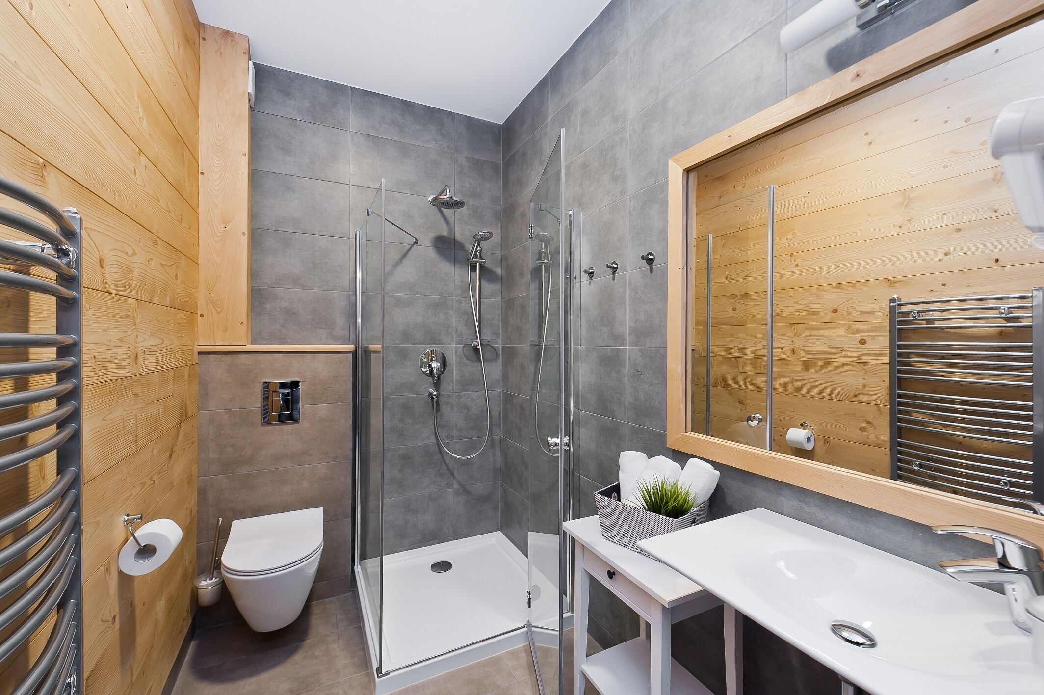 A modern bathroom with a glass-enclosed shower, a white toilet, and a sink with a mirror.