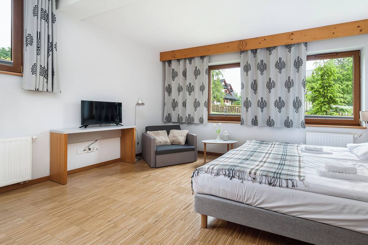 Une chambre à coucher moderne avec un lit, un bureau, une chaise et un téléviseur.