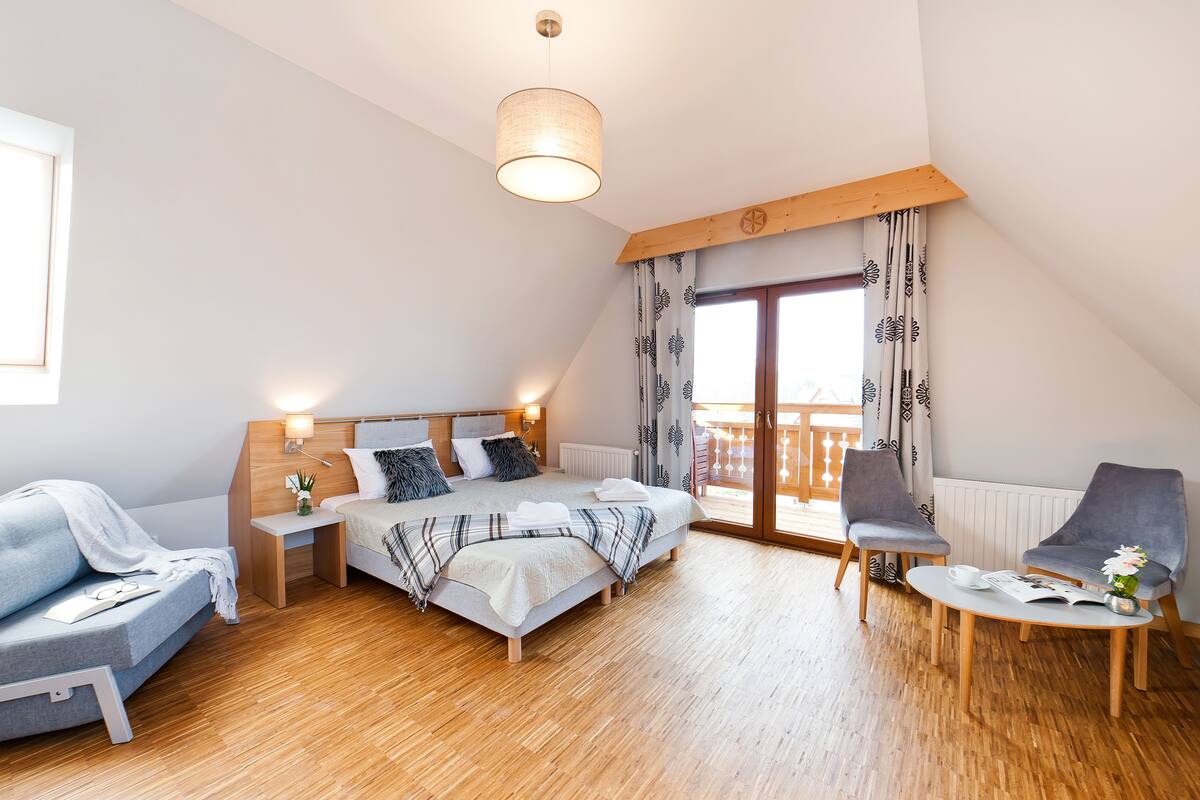 Une chambre à coucher moderne avec un lit, des tables de chevet, un canapé, une chaise et une table.