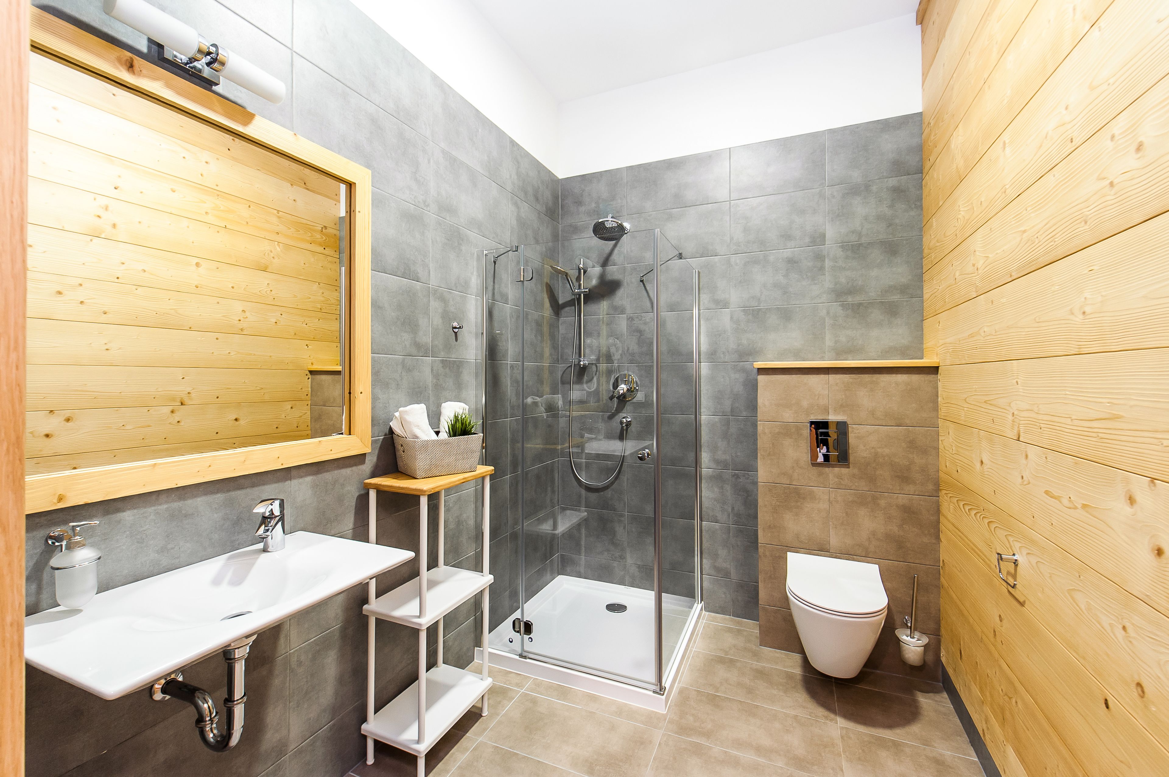 A modern bathroom with a glass-enclosed shower, a wooden vanity with a sink, and a toilet.