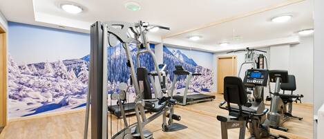 A gym with cardio machines, weight machines, and a mirrored wall.