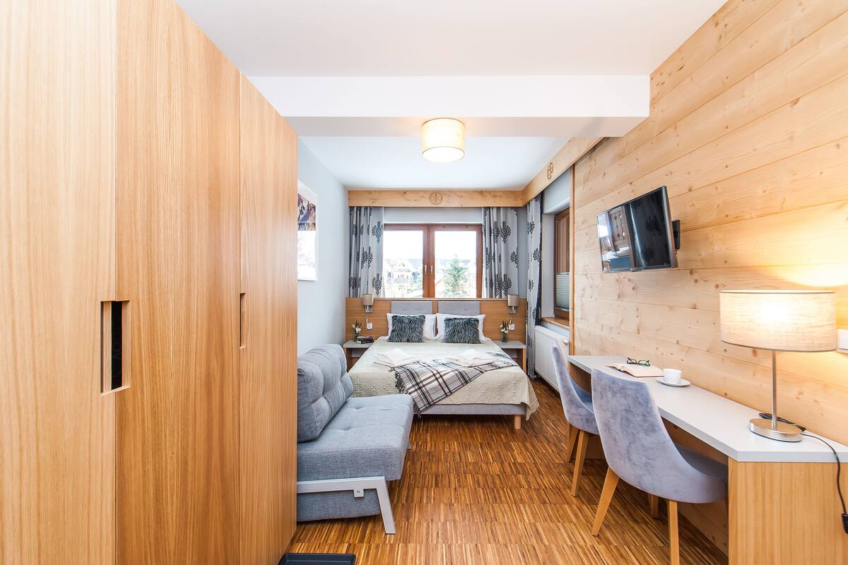 Une pièce de taille modeste comprenant un lit, un bureau et un canapé.