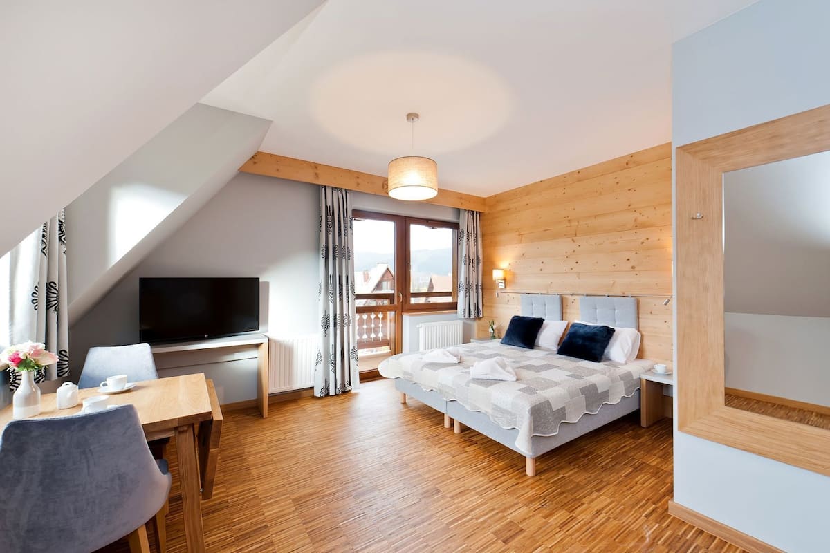 Une chambre d’hôtel avec un lit, un bureau, une télévision et un balcon avec des rideaux.