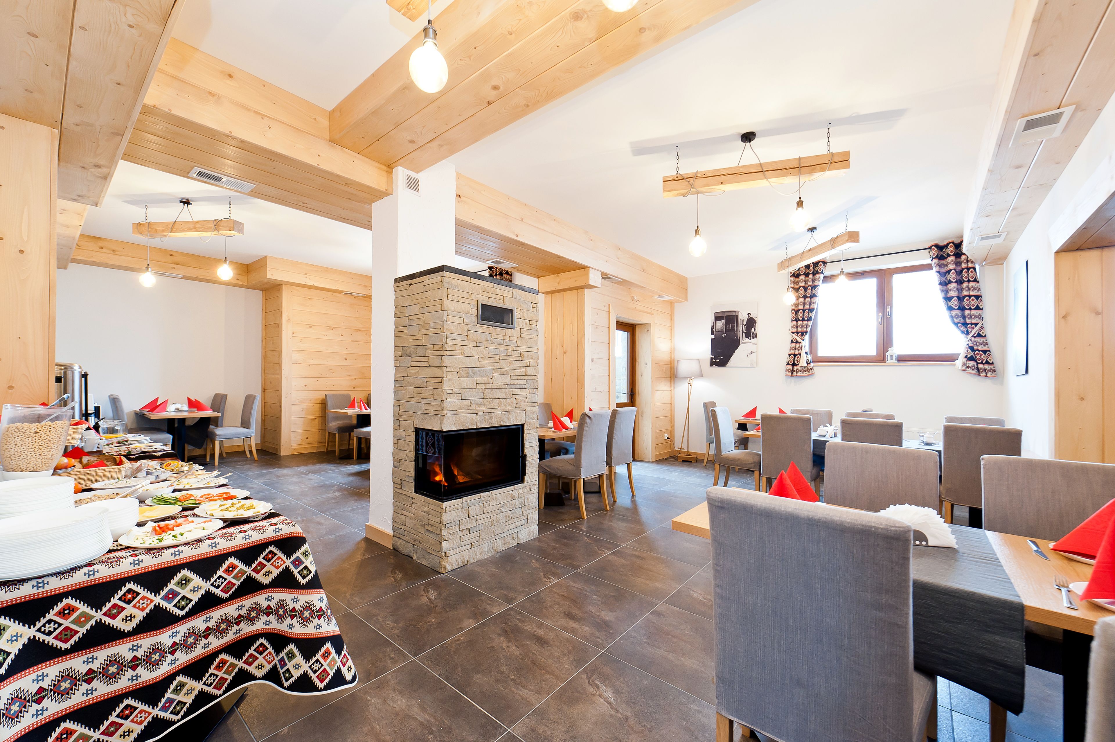A dining area with a stone fireplace, wooden beams, and modern furnishings.