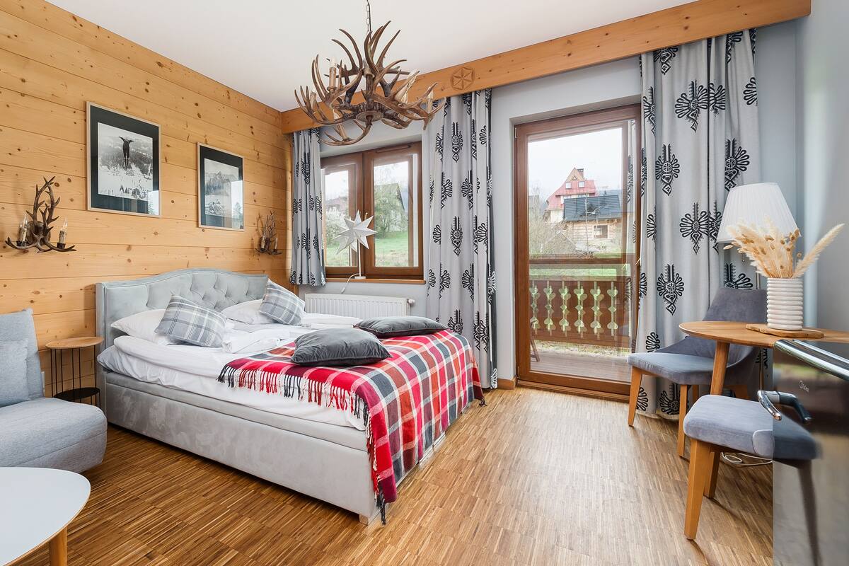 Une chambre confortable avec un lit, un canapé, une petite table et un balcon agrémenté de rideaux à motifs.