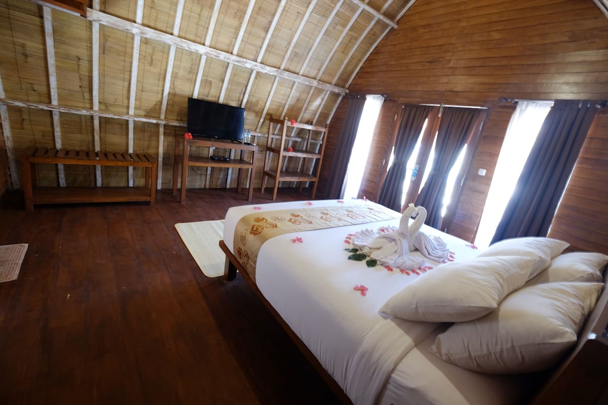 A room with a bed, a television, a desk, and a window.