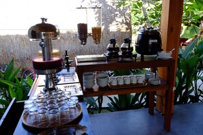 A buffet setup with a coffee machine, a food dispenser, and a variety of dishes and utensils.