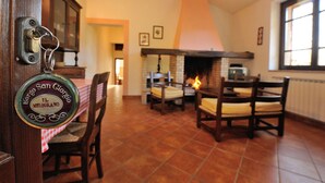 A dining area with a fireplace, wooden chairs, and a checkered tablecloth. - Borgo Saint George (Otricoli)