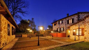 A stone building with a stone facade and wooden shutters, a paved courtyard with a stone pathway, and a grassy area. - Borgo Saint George (Otricoli)