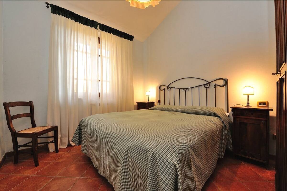 Une chambre à coucher avec un lit, deux lampes de chevet, une chaise et une table de chevet.