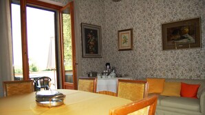 A dining area with a table, chairs, a sofa, and a kitchen area with a stove and sink. - Stunning private villa for 8 guests with WIFI, private pool, TV, terrace, pets allowed and parking (Corchiano)