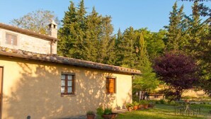 Una casa de piedra rústica con techo de tejas, un pequeño porche y varias macetas con plantas.