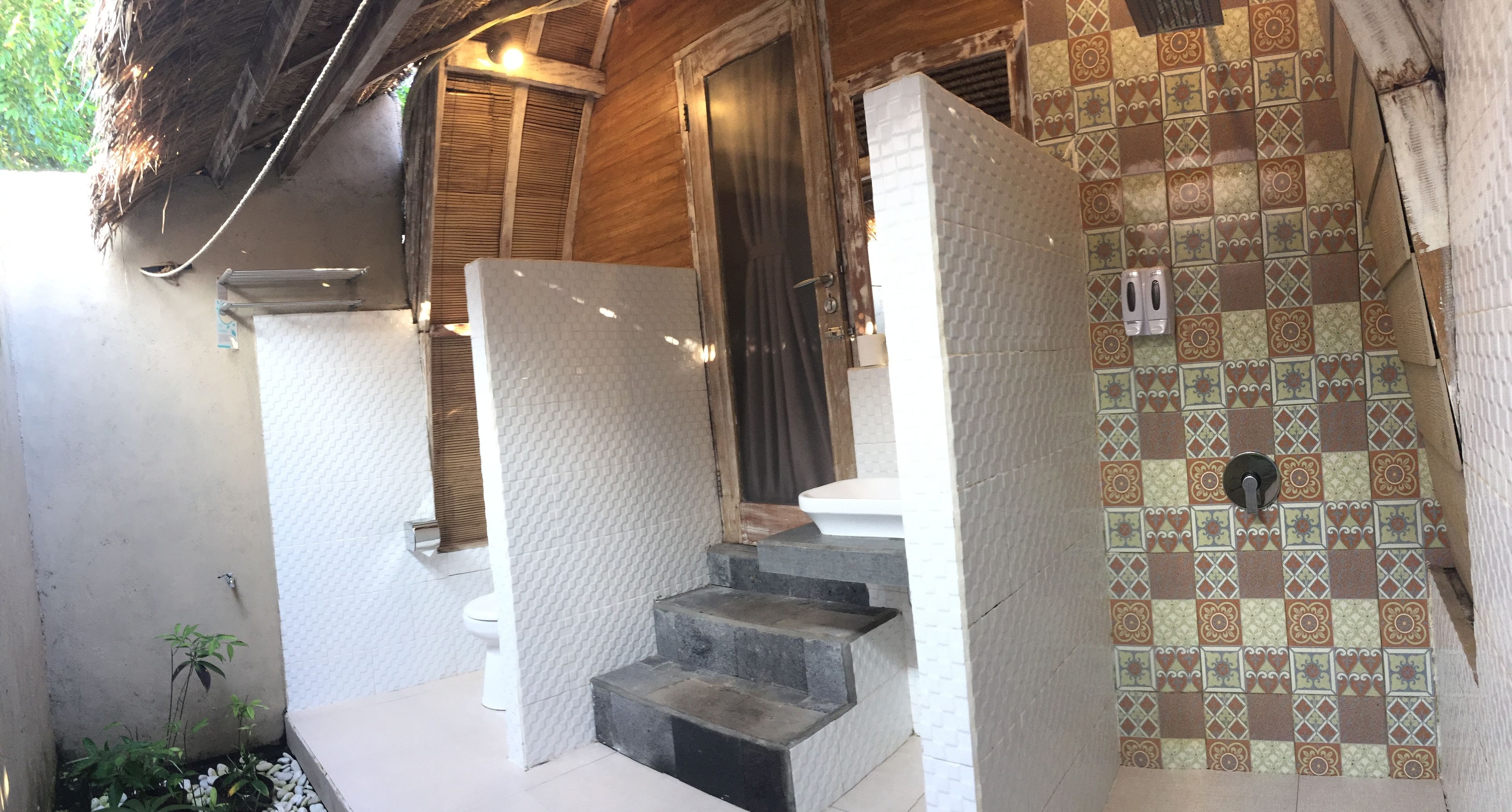A bathroom with a tiled shower, a toilet, and a sink.