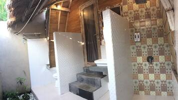 Casa de banho com chuveiro azulejado, sanita e lavatório.