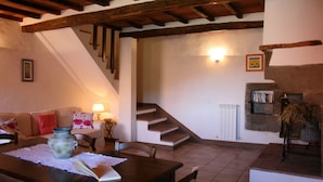 A cozy living room with a wooden staircase, a fireplace, and a dining area with a table and chairs. - Stunning private villa with private pool, WIFI, TV, pets allowed and parking, close to Cortona (Cortona)