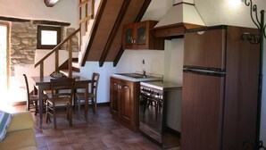 A kitchen with wooden cabinets, a stove, and a refrigerator. There is a dining table with chairs and a staircase leading to an upper level. - Stunning private villa with private pool, WIFI, TV, pets allowed and parking, close to Cortona (Cortona)