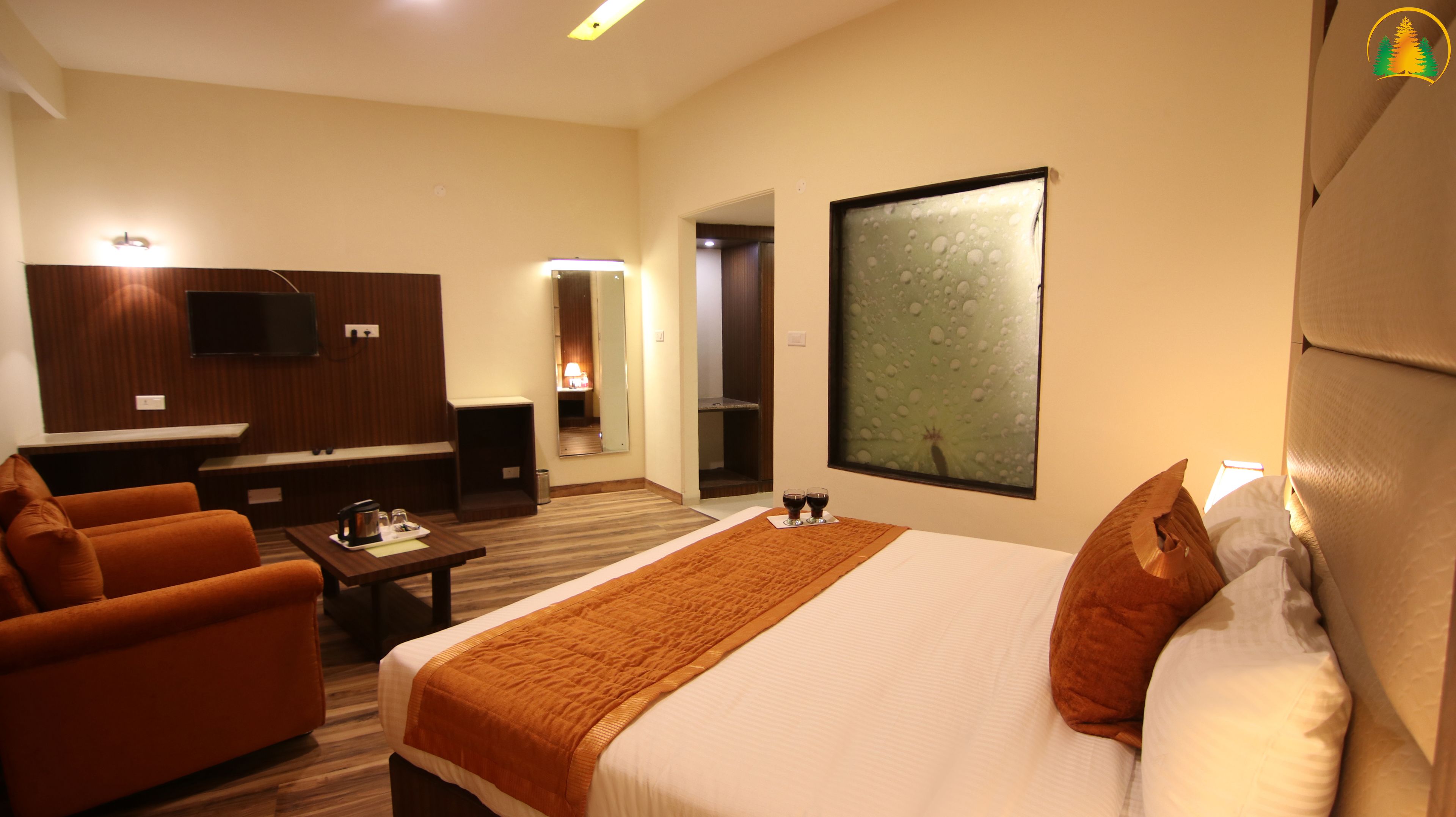 Une chambre d’hôtel avec un lit, un canapé, une télévision, un miroir et une fenêtre donnant sur un paysage agréable.