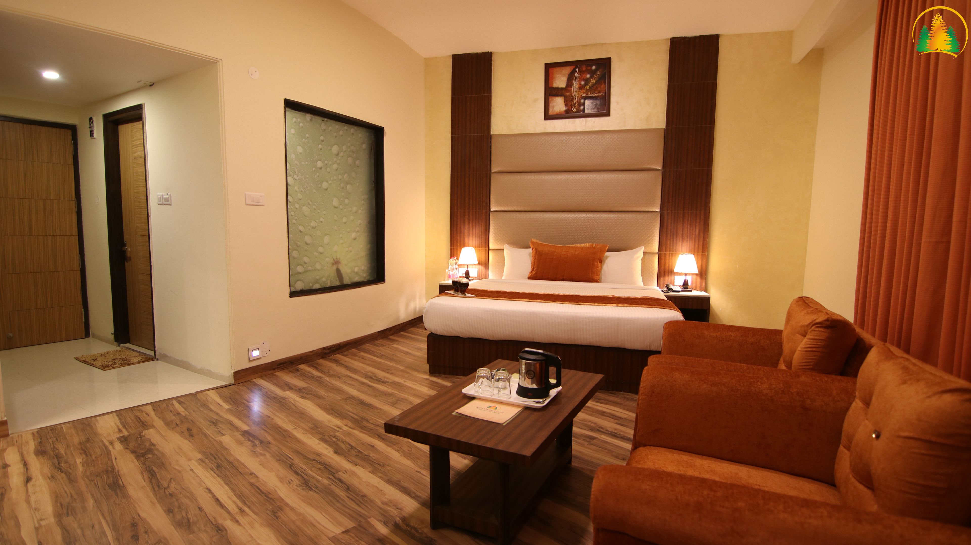 A hotel room with a bed, a sofa, a coffee table, a painting, and a nightstand with a lamp.