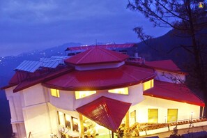 A multi-story building with a red roof, multiple windows, and solar panels on the roof. - Kufri Pacific Resort (Shimla)