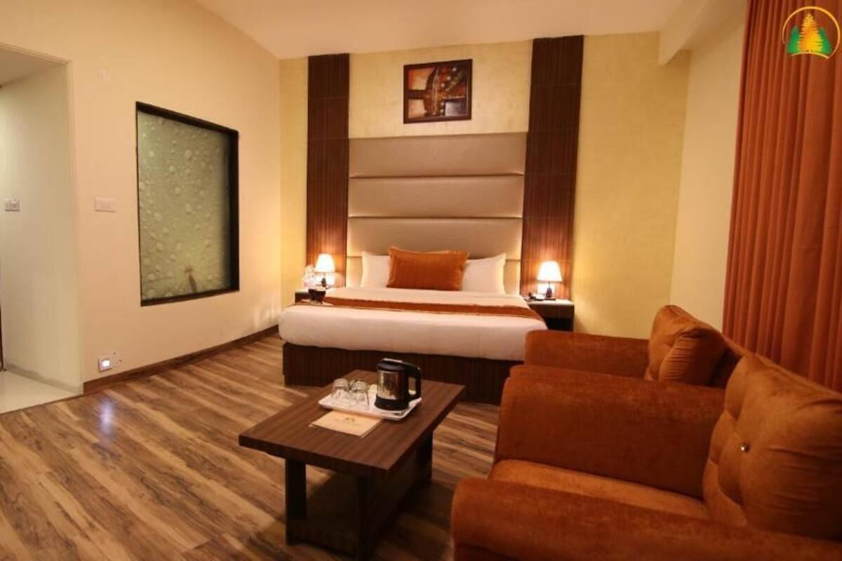 A hotel room with a bed, a sofa, a coffee table, and a painting on the wall.