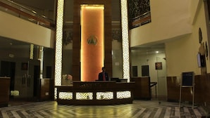 Zona de recepción con una columna central, una recepcionista y un mostrador.