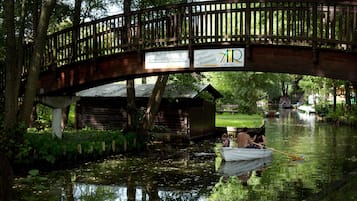 Un puente de madera sobre un río tranquilo, con una barca y gente.