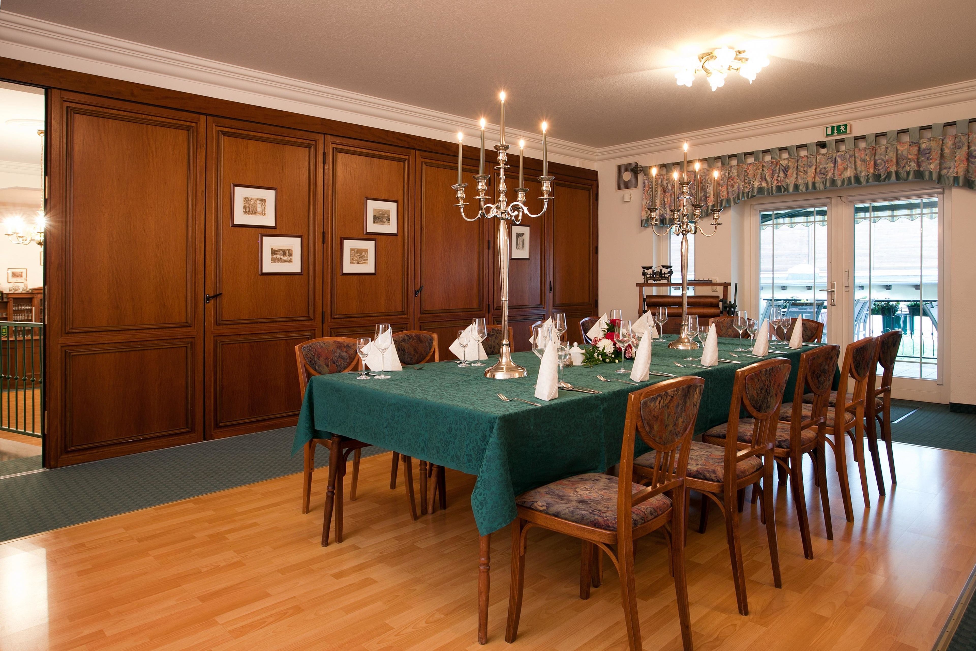 Un comedor formal con una larga mesa dispuesta para una comida, paneles de madera en las paredes y un candelabro.
