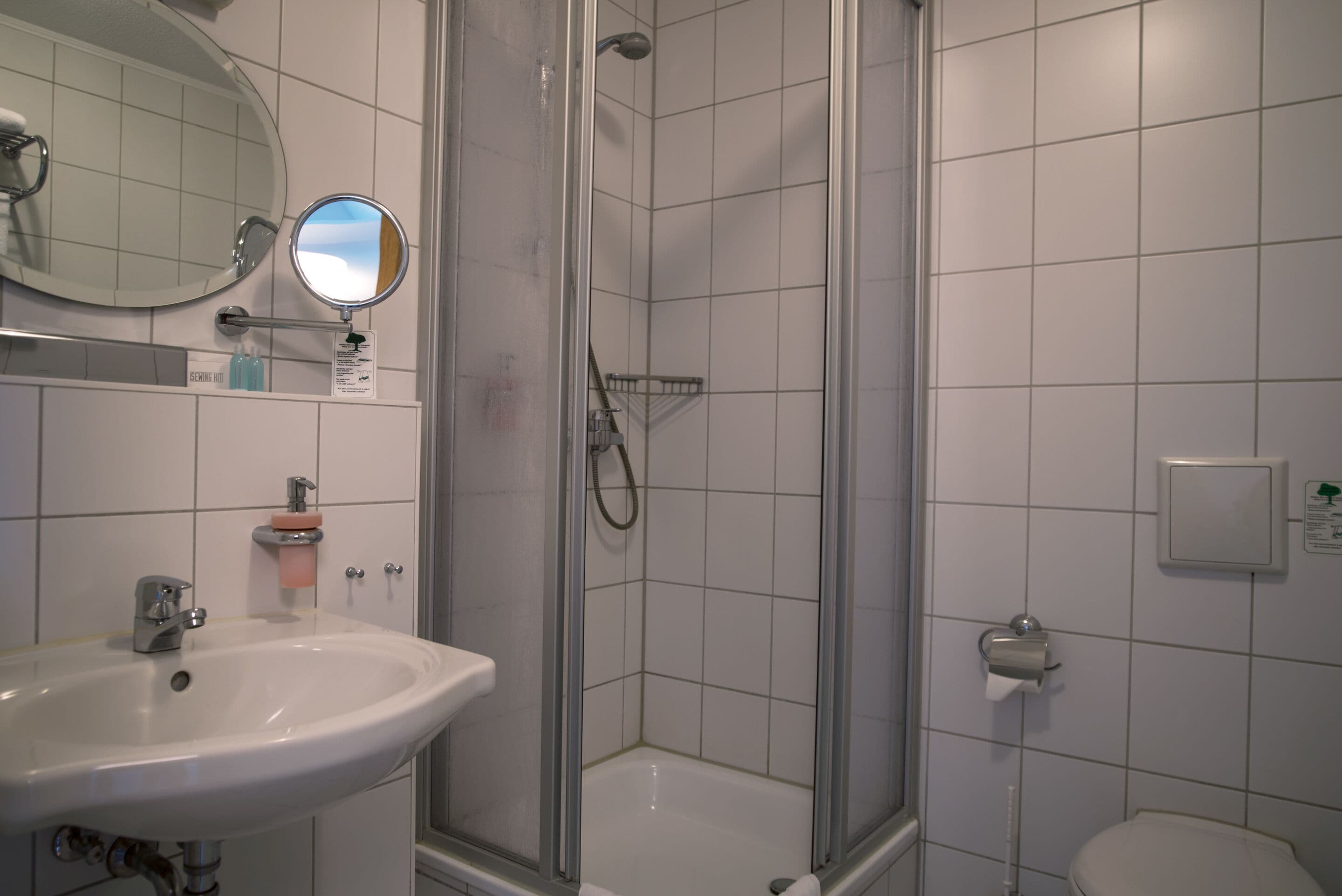 Een badkamer met een wastafel, spiegel, douche en toilet.
