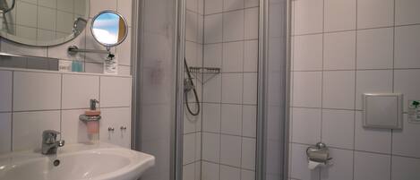 Een badkamer met een wastafel, spiegel, douche en toilet.