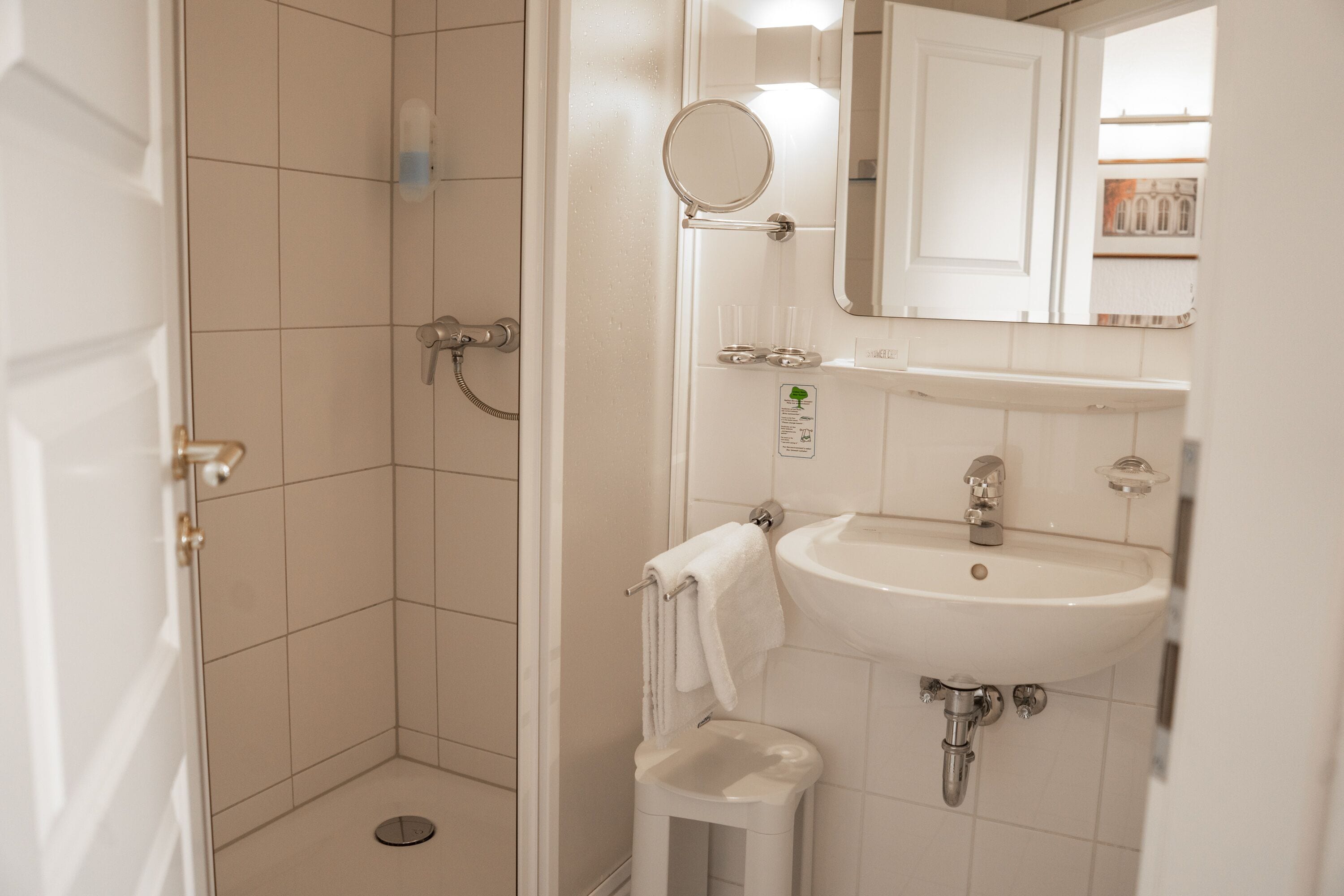 A bathroom with a shower, sink, and mirror.