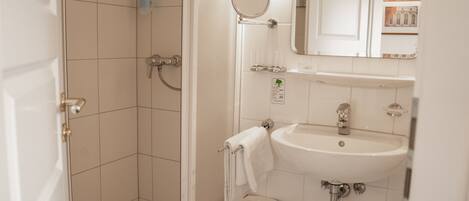 A bathroom with a shower, sink, and mirror.