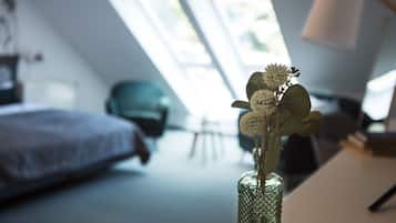 A room with a bed, a chair, and a desk with a lamp. There is a window with a view of the outside.