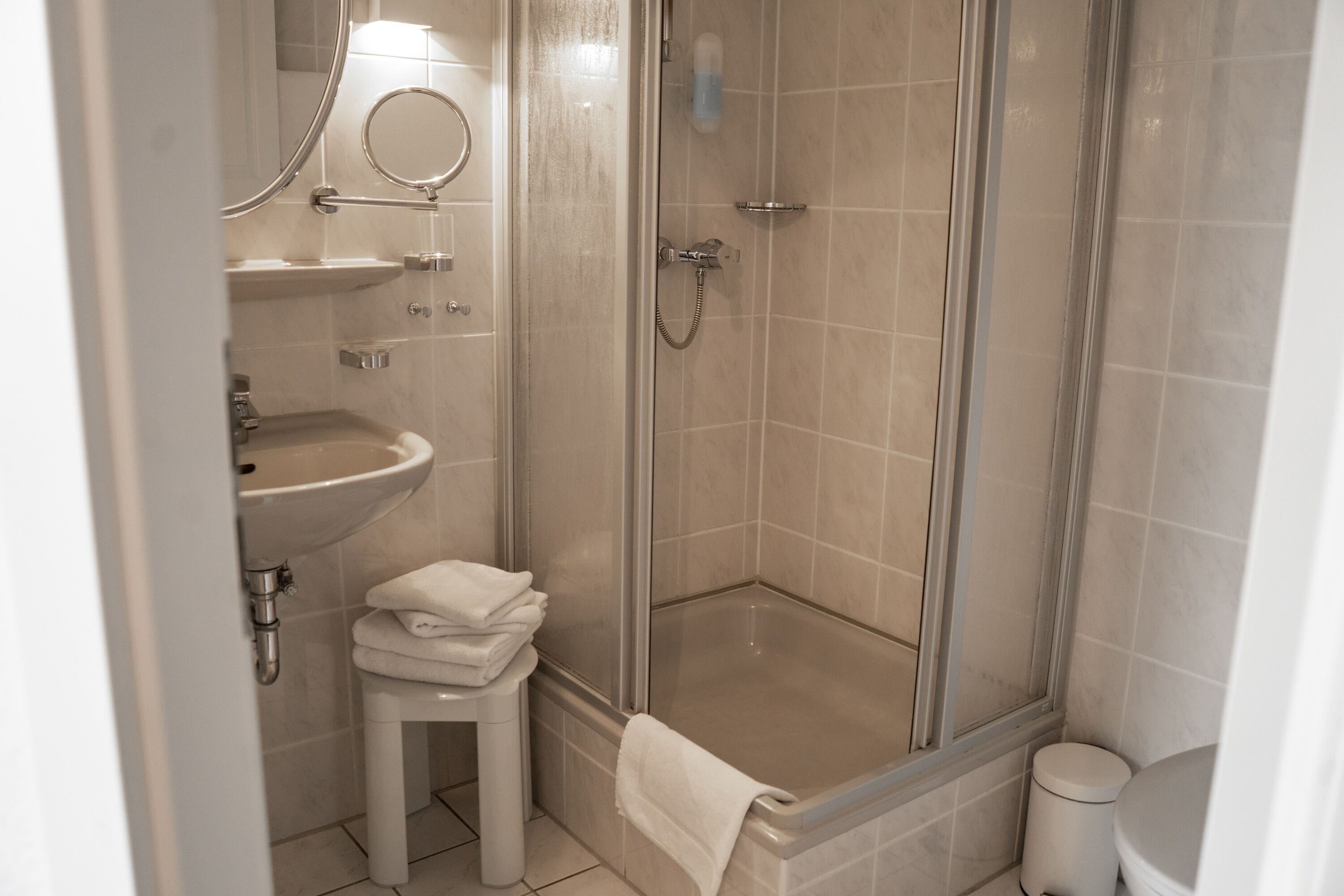 Un baño con ducha envuelta en vidrio, lavamanos y retrete.