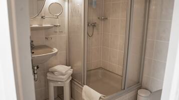 A bathroom with a glass-enclosed shower, a sink, and a toilet.