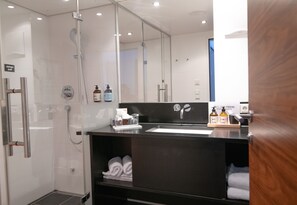 A modern bathroom with a glass-enclosed shower, a black vanity with a mirror, and neatly folded towels.