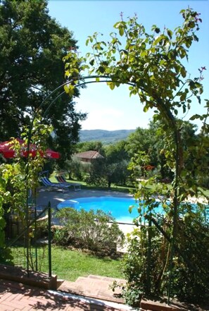 Une piscine offrant une vue sur le paysage environnant, avec notamment des arbres et une chaîne de montagnes au loin.
